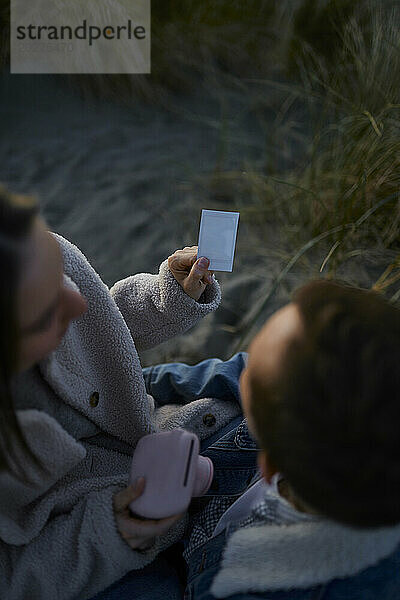 Junges Paar betrachtet Fotodruck  der am Strand entsteht