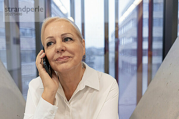 Lächelnde ältere Geschäftsfrau  die am Smartphone spricht