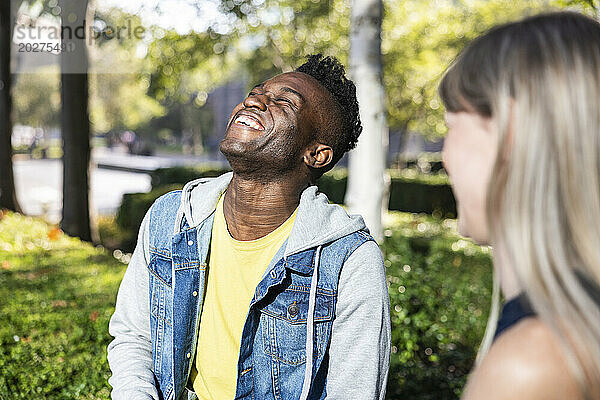 Young man laughing with female friend in city