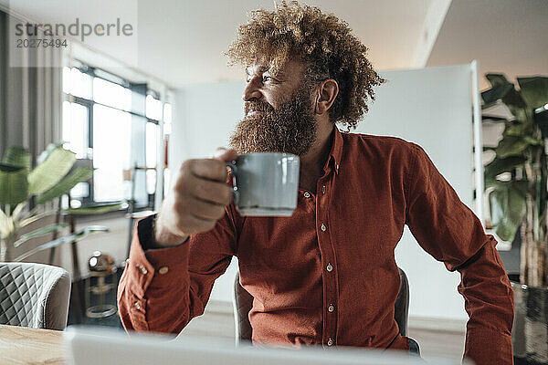 Reifer Geschäftsmann mit Afro-Frisur hält Kaffeetasse in der Bürokantine