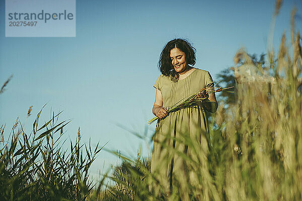 Smiling woman standing in field on sunny day