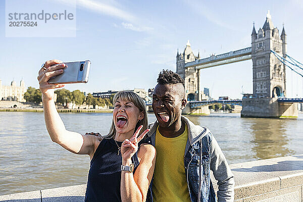 Gemischtrassige Touristenfreunde  die im Urlaub die Zunge herausstrecken und ein Selfie machen