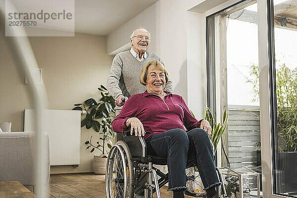 Glücklicher Mann und Frau sitzen zu Hause im Rollstuhl