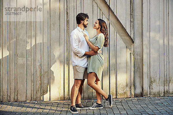 Loving young couple standing in front of wall