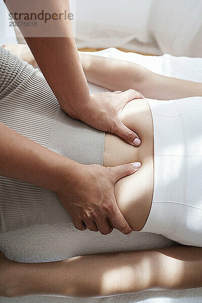 Osteopath treating patient's abdomen in treatment room
