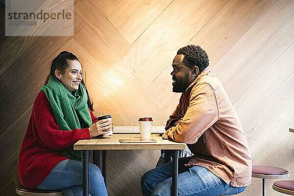 Lächelnde Frau sitzt mit Mann im Café