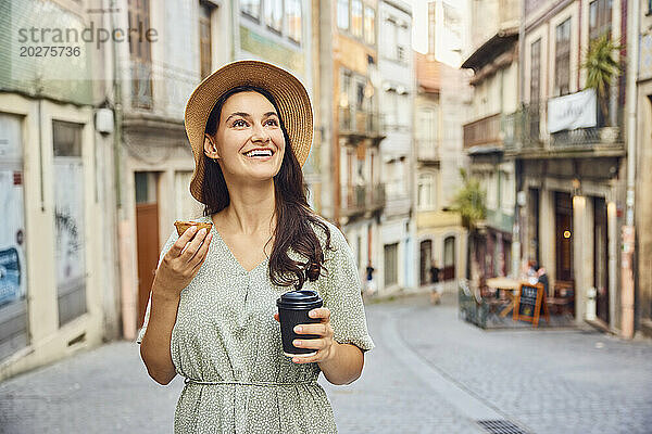 Lächelnde Frau mit Kaffeetasse und traditionellem Dessert Pastel de Nata