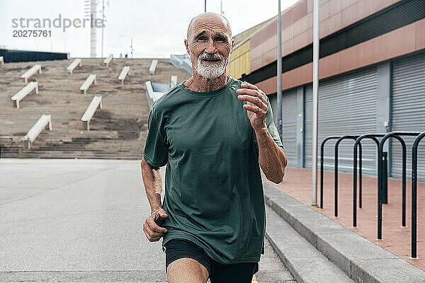 Entschlossener aktiver älterer Mann läuft auf Fußweg