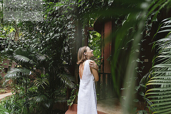 Glückliche Frau steht im tropischen Garten