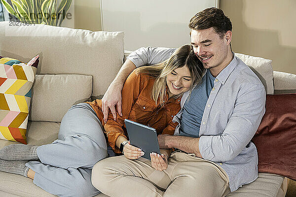 Liebevolles junges Paar nutzt Tablet-PC auf dem Sofa