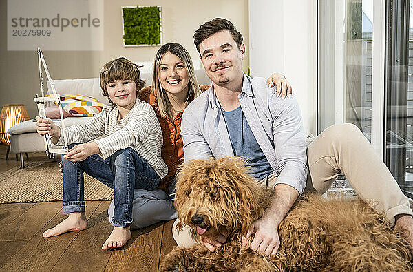 Glückliche Familie mit Musterhaus und Hund  der im Wohnzimmer sitzt