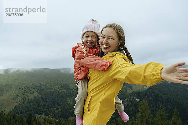 Glückliche Mutter trägt Tochter auf dem Berg