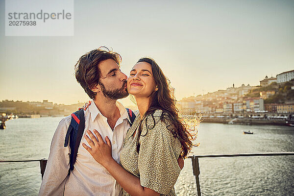 Glücklicher Mann küsst Frau vor dem Fluss Douro in Porto  Portugal