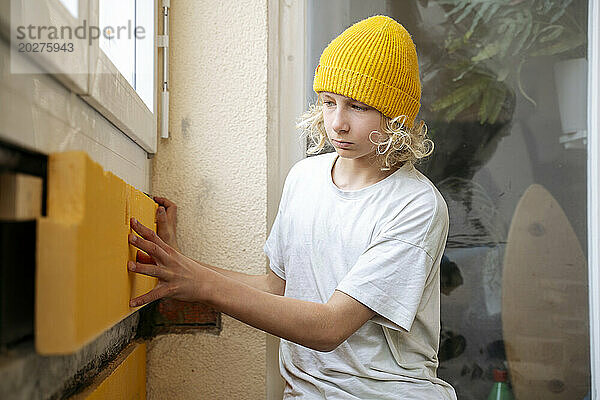 Junge installiert Isolierung an Wand in Zimmer  das gerade renoviert wird