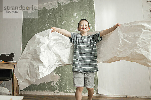 Playful boy with angel wings from old wallpaper at home