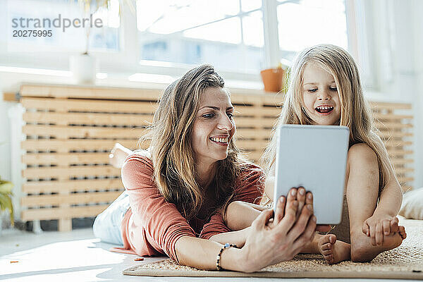 Glückliche Mutter und Tochter nutzen Tablet-PC zu Hause