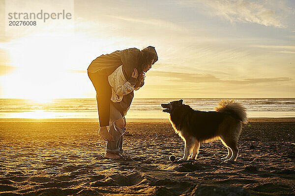 Glückliches junges Paar genießt es mit Hund am Strand