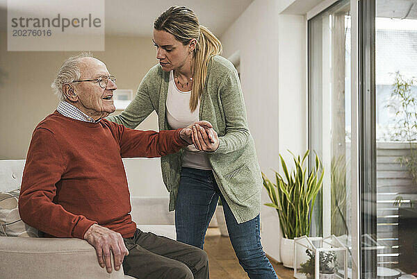 Home caregiver taking care of senior man in living room