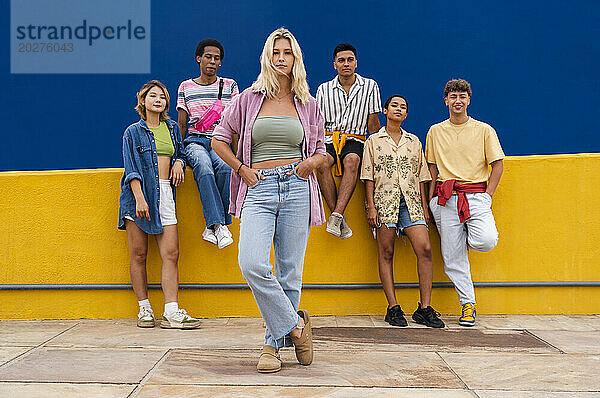 Confident blond woman standing in front of group of friends with hands on hips