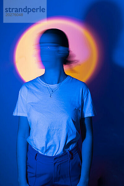 Frau steht in Neonbeleuchtung vor blauem Hintergrund