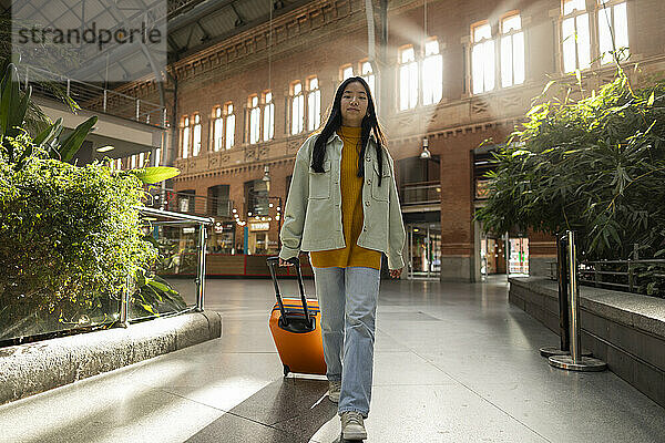Junge Frau läuft mit Koffer am Bahnhof