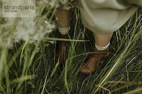 Woman wearing boots and standing amidst grass in field