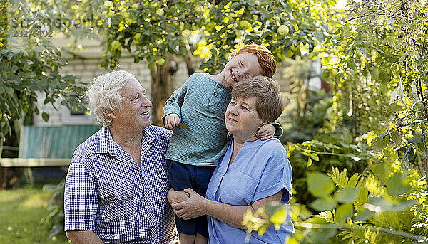 Happy boy having fun with grandparents in garden