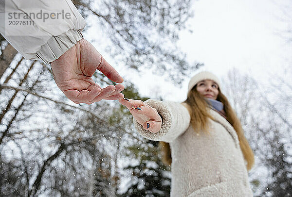 Junge Frau greift im Winterpark nach der Hand des Mannes