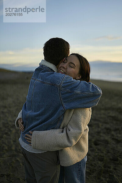 Smiling young woman embracing boyfriend at beach