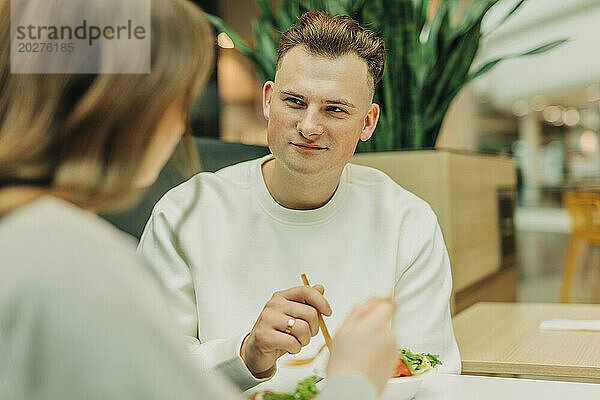 Junger Mann isst mit Freundin im Einkaufszentrum Salat