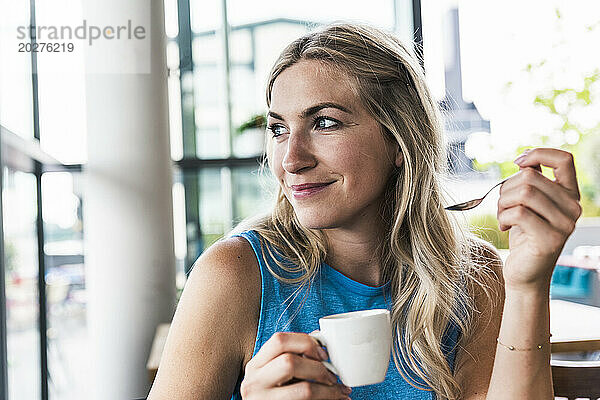 Lächelnde Frau hält Kaffeetasse im Restaurant