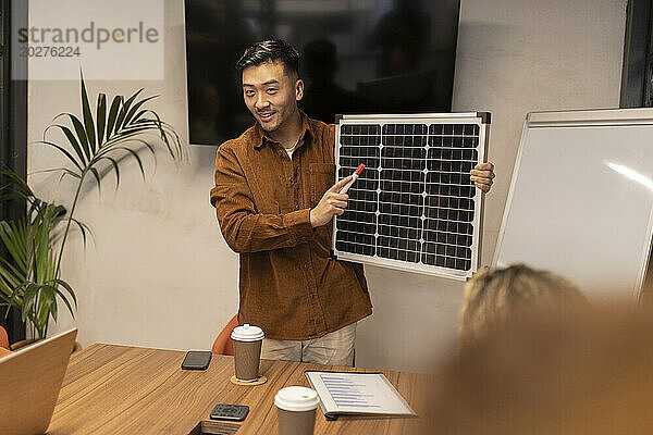 Businessman showing solar panel in meeting at office