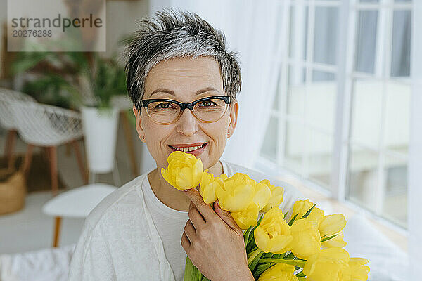 Lächelnde Frau mit einem Strauß Tulpen zu Hause