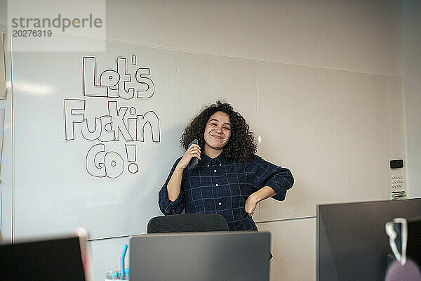 Lächelnde Geschäftsfrau steht neben Whiteboard im Büro