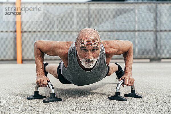 Entschlossener älterer Mann macht Plankenübungen an Griffen