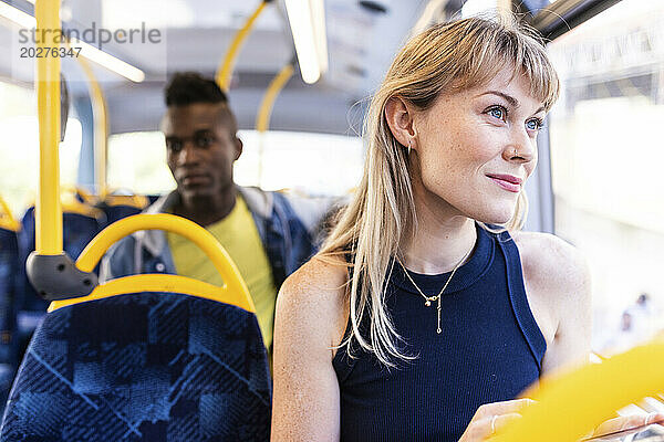 Lächelnde Frau  die mit einem Freund im Bus aus dem Fenster schaut