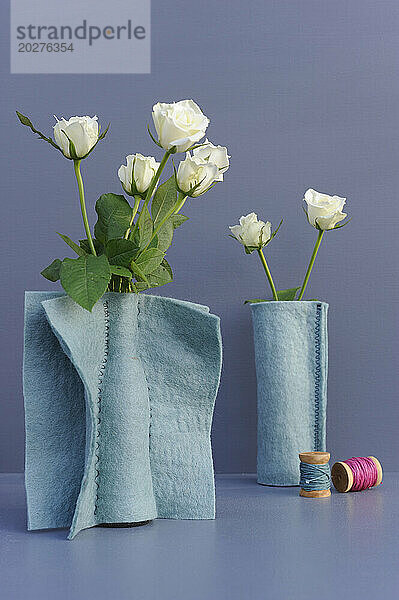 White roses in felt covered vases