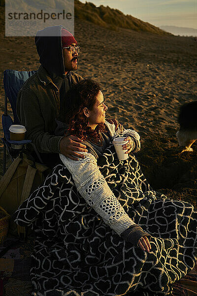 Junges Paar entspannt sich bei Sonnenuntergang am Strand