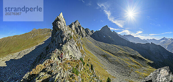 Austria  Tyrol  Sun shining over female hiker following Aschaffenburger Hohenweg trail in Zillertal Alps