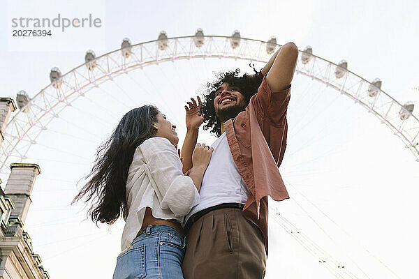 Glückliches Paar steht vor dem Riesenrad unter freiem Himmel in London