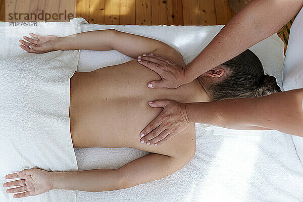 Osteopath massaging patient's back in treatment room