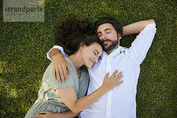 Liebevolles junges Paar  das auf Gras liegt