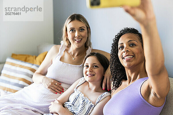 Lächelnde Frau  die zu Hause ein Selfie mit der Familie macht