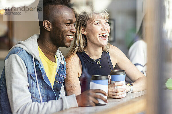 Junge glückliche Freunde schauen aus dem Fenster im Café