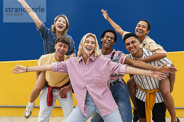 Gruppe junger Freunde in farbenfroher Kleidung posiert glücklich vor der Wand