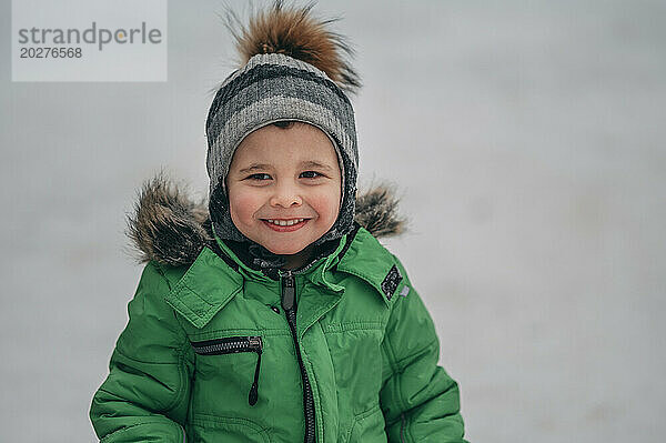 Lächelnder Junge  der im Winter warme Kleidung trägt