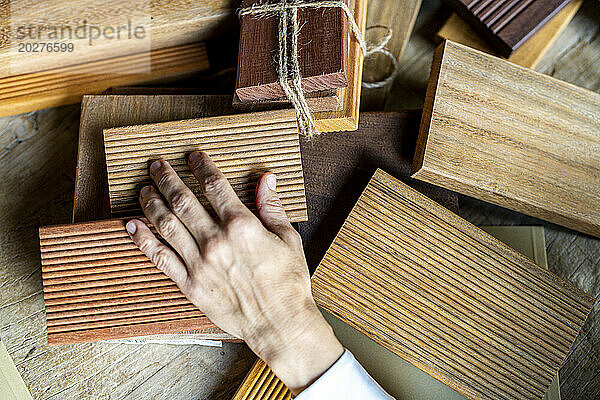 Hand einer reifen Geschäftsfrau  die Holzproben auf dem Schreibtisch auswählt