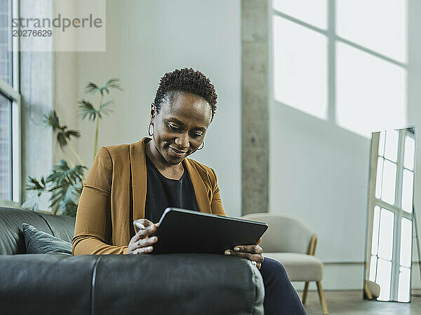 Geschäftsfrau sitzt mit Tablet-PC auf dem Sofa im Büro