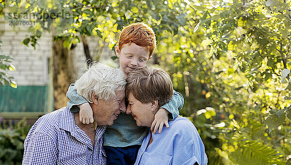Glückliches älteres Paar mit seinem Enkel im Garten