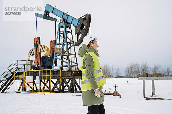 Ingenieur steht im Winter am Ölförderfeld